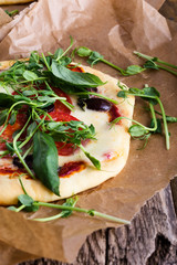 Homemade pizza with tomatoes and sprouts topping on rustic table