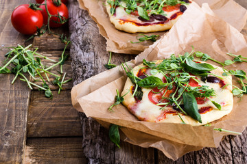 Homemade pizza with tomatoes and sprouts topping on rustic table