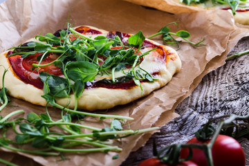 Homemade pizza with tomatoes and sprouts topping on rustic table