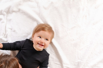 Portrait of beautiful mom playing with her baby in bedroom