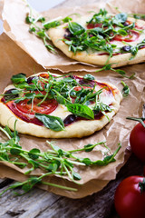 Homemade pizza with tomatoes and sprouts topping on rustic table