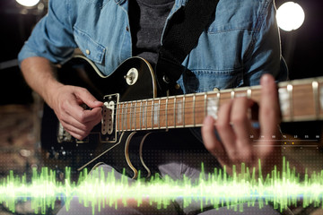 Obraz na płótnie Canvas close up of man playing guitar at studio rehearsal
