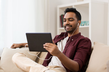man in earphones with tablet pc listening to music
