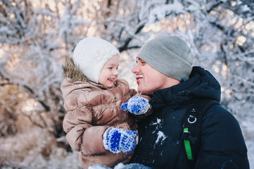 Family of father and his adorable little daughter outdoors on beautiful winter snowy day.