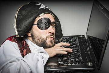 Hacking, hacker, cyber criminal with pirate clothes, attempt to hack a laptop