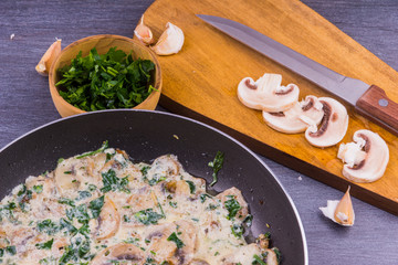 Creamy sauce with mushrooms and greens in a frying pan