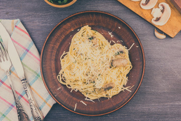 Spaghetti, Pasta with mushrooms in creamy sauce in a plate on a wooden table