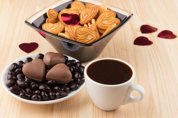 Sweets in a saucer and shortbread in a vase, and a Cup of coffee on a wooden  the table.
