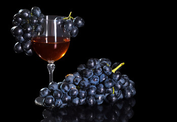 Grape wine and a bunch of grapes on a black background.