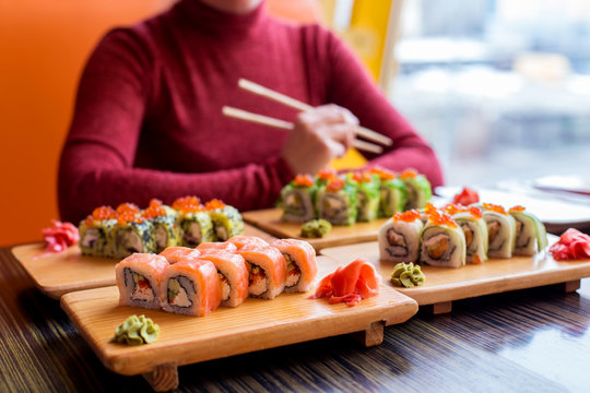 Woman eating sushi rolls at the table