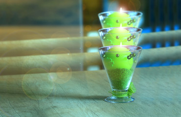 Fototapeta Piękny kielich z zieloną palącą się świecą na stole w restauracji. obraz