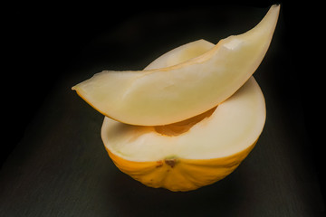 The cut yellow sweet melon on a black background