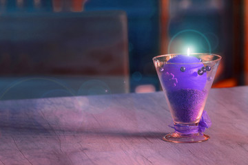 Fototapeta Piękny kielich z fioletową palącą się świecą na stole w restauracji. obraz