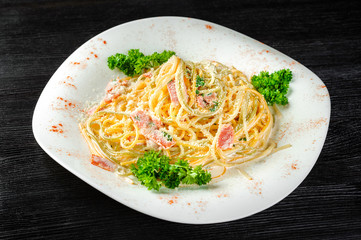 Pasta Carbonara on the white plate on a black background