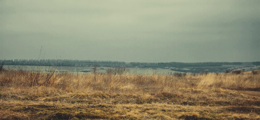 Early spring, dirt road, depressed rural landscape under a cloudy sky, selective focus