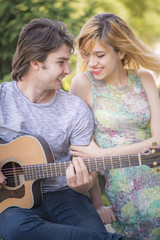 Young cute couple enjoying sunny day, boyfriend playing gutiar for his girlfriend