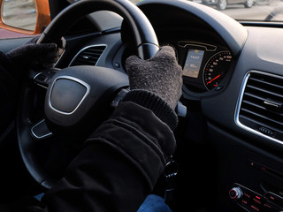 Female hands in the gloves on the steering wheel of a car