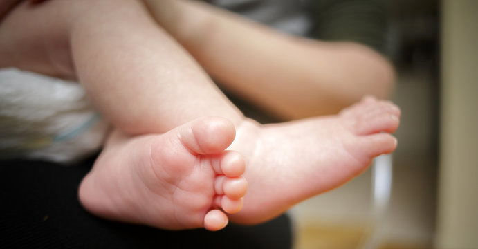 Feet of newborn baby in the hand of mother