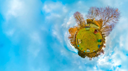 Green little planet with trees and apiary, white clouds and soft blue sky. Tiny planet with nature at autumn. Mini planet Earth with green grass. Little planet with 360 viewing angel.