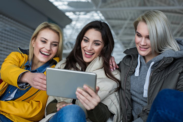 Technology concept. Trio of ladies having fun with gadget. They are staring at device and laughing