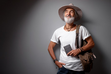 Enjoying travel. Studio portrait of handsome senior man with gray beard and hat.