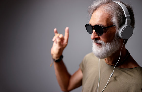 Enjoying the sound of music. Studio portrait of handsome senior man with gray beard and headphones.