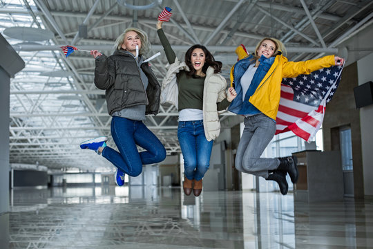 Dreams come true. Content girls jumping for joy with flags of united states. They are going traveling abroad