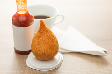 Coxinha is a deep fried food, traditional in Brazil. Snack, pepper sauce and coffee. Bar food. Selective focus.