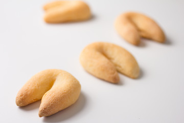 Cheese bread known as Chipa in Brazil, shaped like a horseshoe. Snacks spread on white table. Selective focus, minimalism.