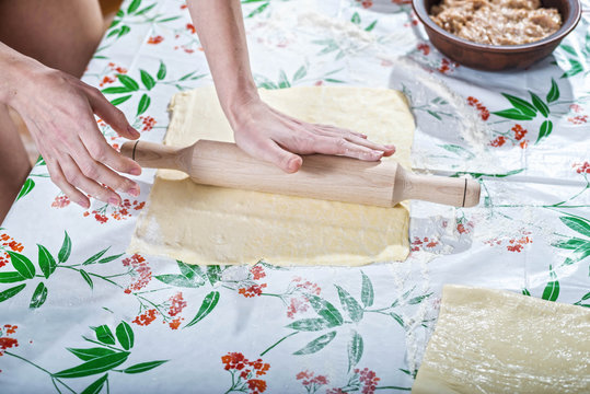Female hands rolling out dough for homemade baking.