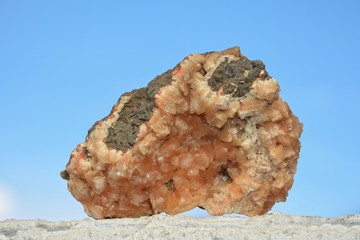Orangener Mineralien Quarz Stein im Sonnenlicht mit blauem Himmel