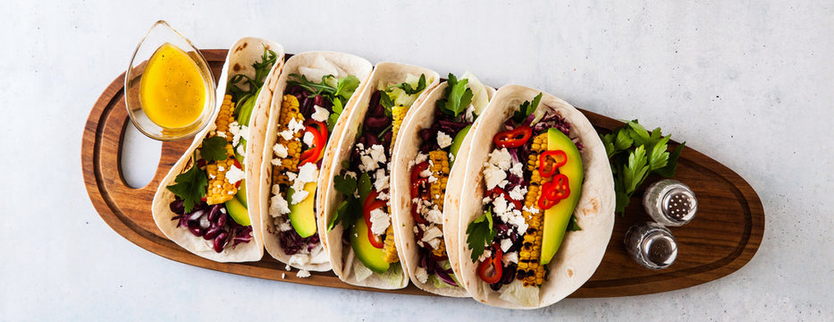 Vegetarian snack tacos with grilled vegetables, avocado, feta cheese, salad with small sweet peppers and sauce with lemon and olive oil. food background banner