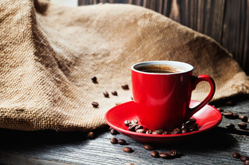 cup of fresh coffee with coffee beans on wooden table