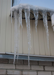 Dangerous large icicles on the roof of a village house