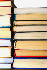 Stack of different books on a table against a white wall background