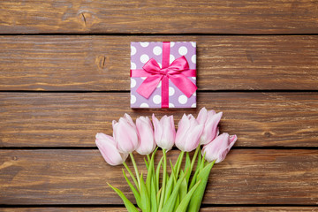 Gift box and tulips on wooden background
