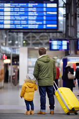 Little boy and his father in international airport or on railway station platform looking on...