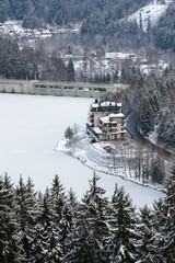 Aerial view of concrete Brezova dam with hydroelectric power plant and road to Karlovy Vary from Jungmann gazebo, snowy winter day, Czech Republic
