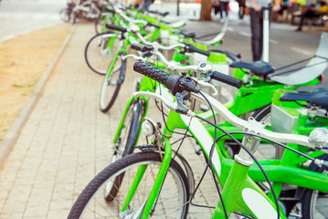 Row of public bicycle on rental station on city background. Eco-friendly and convenient transportation in the city. Close up, selective focus. Space for text.