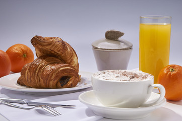 Fresh croissants, orange juice, coffee and oranges. Continental breakfast on white table