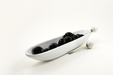 Black olives stock images. Black olives in a white ceramic bowl. Black olives on a white background. Healthy snack images