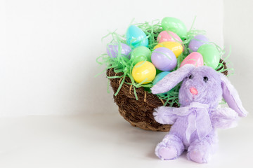 Purple bunny with basket of colorful Easter eggs.