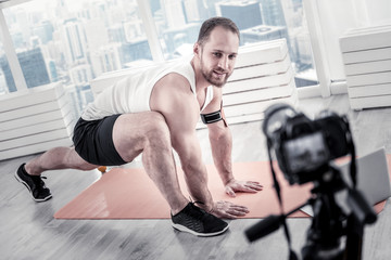Fototapeta na wymiar Repeat after me. Pleasant nice male blogger stretching muscles while recording video for creating blog