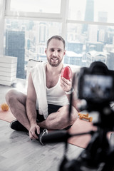 Vegetable with vitamins. Pleasant jolly male blogger creating video while posing on mat board and carrying bell paper