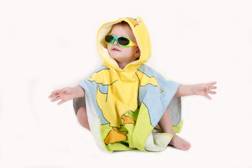 A happy child in  swimming glasses and a bathrobe after swimming in the form of a duck. The kid plays with a toy duck. The boy is happy in his home with parents and brothers. Hygiene and cleanliness