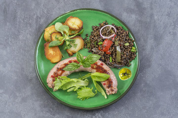 France Grilled Toulouse sausage with roasted potatoaes and salad and lentils on grey background