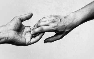 Emotional, black and white photo of two hands at the moment of farewell. The concept of breaking...