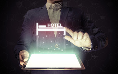 Image of a man with a smartphone in his hands. He presses on the hotel icon. Search and online...