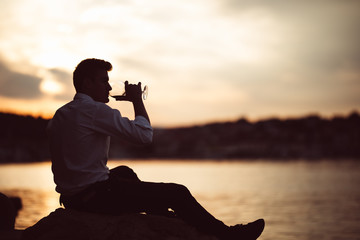 Young stressed business man drinking wine alone.Alcoholic man unhappy with his life,addicted to...
