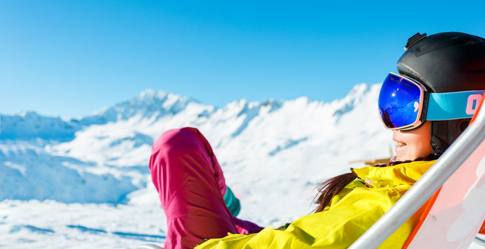 Picture of sports woman in helmet sitting at snowy resort